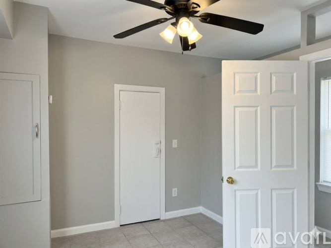 A room with a ceiling fan and three doors.