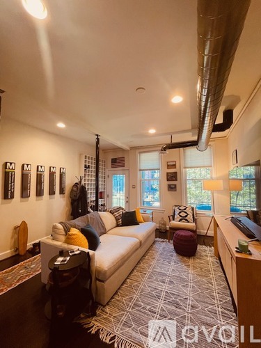 A living room with a white couch and a rug with a geometric pattern.