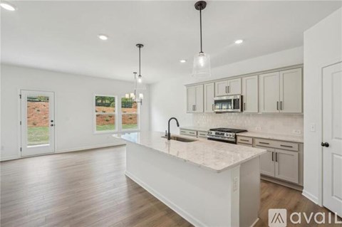 A modern kitchen with a white island and wooden floors.
