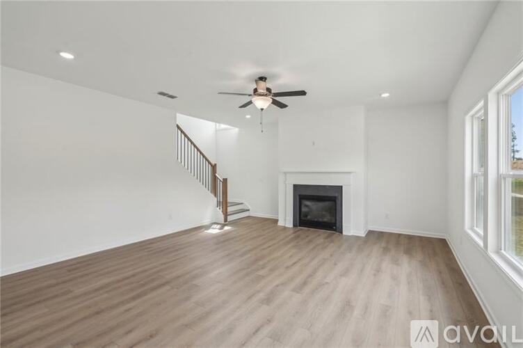 A spacious living room with a fireplace and a ceiling fan.