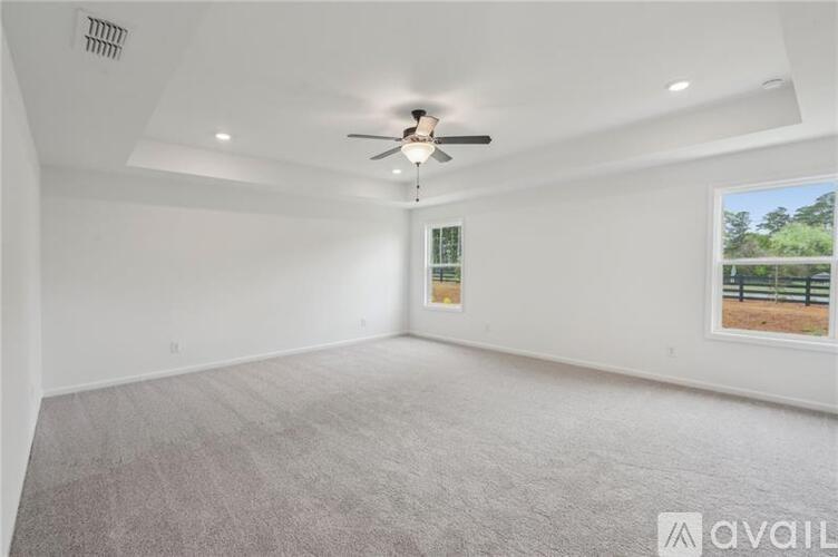 A spacious room with a ceiling fan and a window showing an outdoor scene.