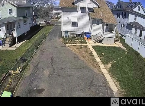 A residential street with houses on both sides and a sidewalk in the middle.
