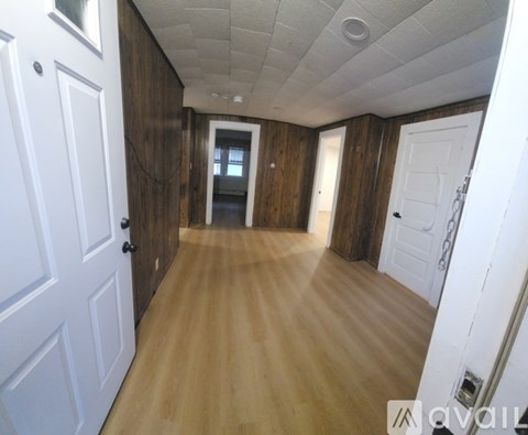 A long hallway with wooden floors and white doors.