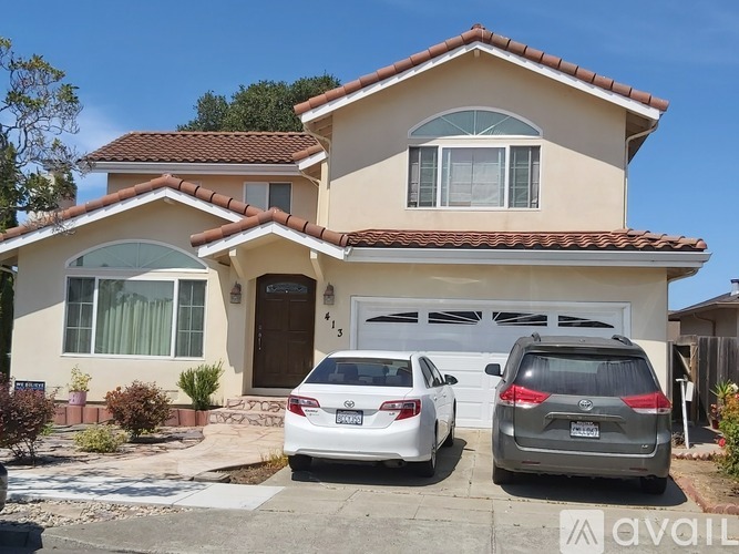 A two-story house with a garage and two cars parked in front.