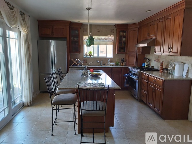 A kitchen with wooden cabinets and a large island with chairs.