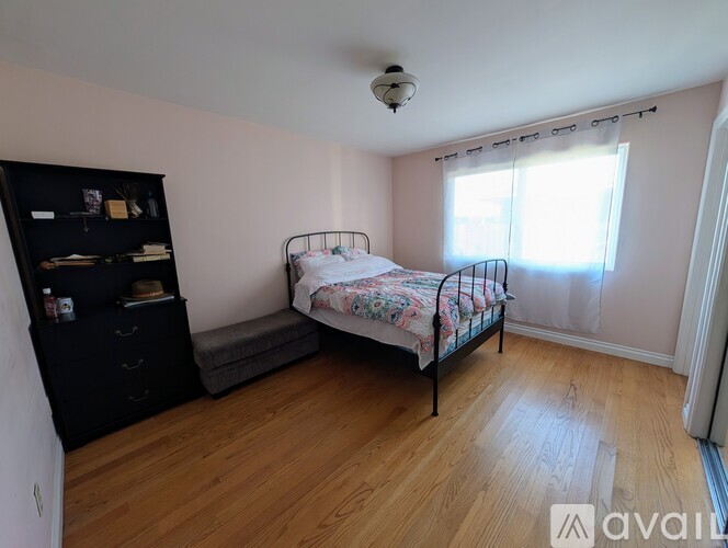 A bedroom with a bed, dresser, and window.