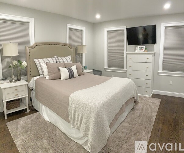 A bedroom with a large bed, a nightstand, and a TV mounted on the wall.
