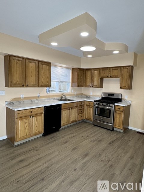 A kitchen with wooden cabinets and a black dishwasher.