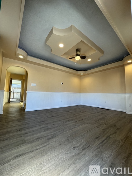 A spacious room with wooden flooring and a ceiling fan.