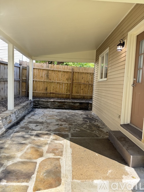 A patio with a stone floor and a wooden fence.