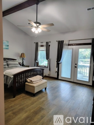 A bedroom with a bed, a bench, and a ceiling fan.