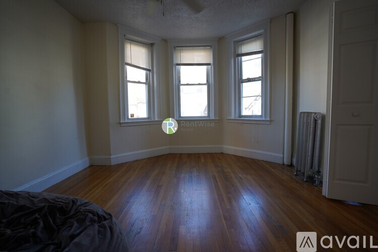 A room with wooden floors and three windows.