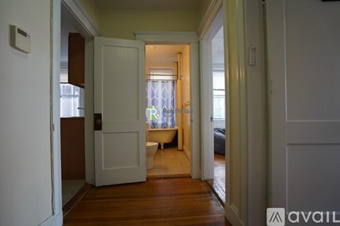 A hallway with a door on the left and a window with blinds on the right.