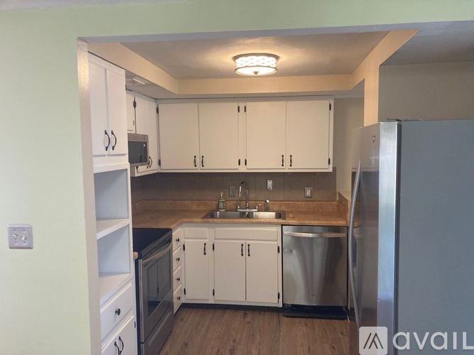A kitchen with white cabinets and a wooden counter top.