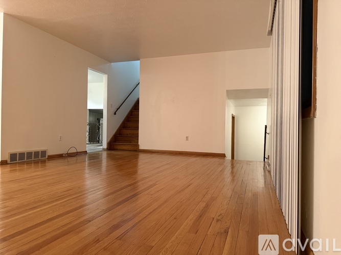 A room with wooden floors and a staircase in the background.