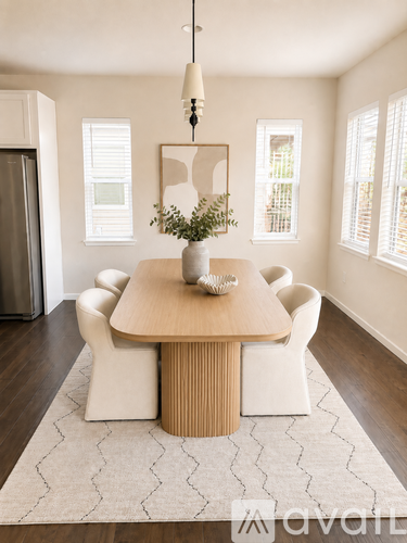 A dining room with a wooden table and white chairs.