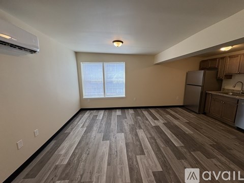 A spacious room with wood flooring and a window overlooking a cityscape.
