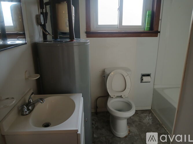 A bathroom with a toilet, sink, and mirror.
