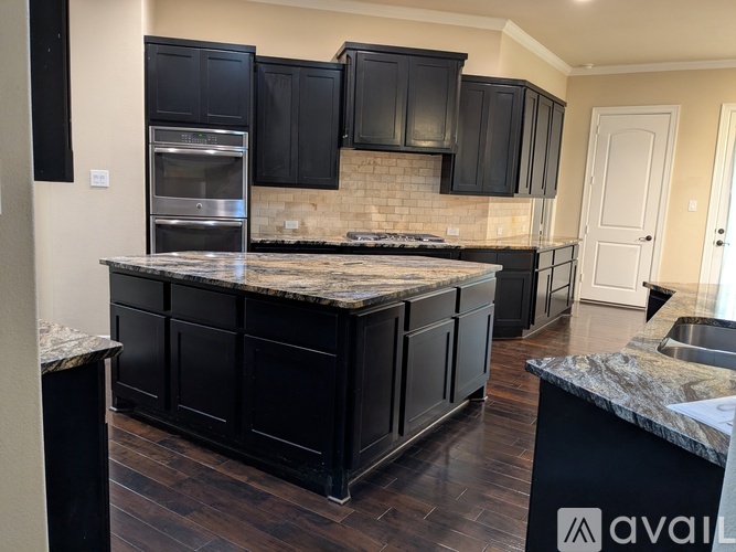 A kitchen with black cabinets and a marble countertop.