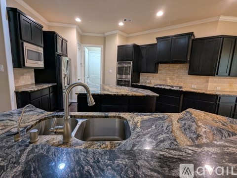 A kitchen with black cabinets and a marble countertop.