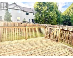 A wooden deck with a house and trees in the background.