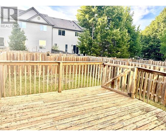 A wooden deck with a house and trees in the background.