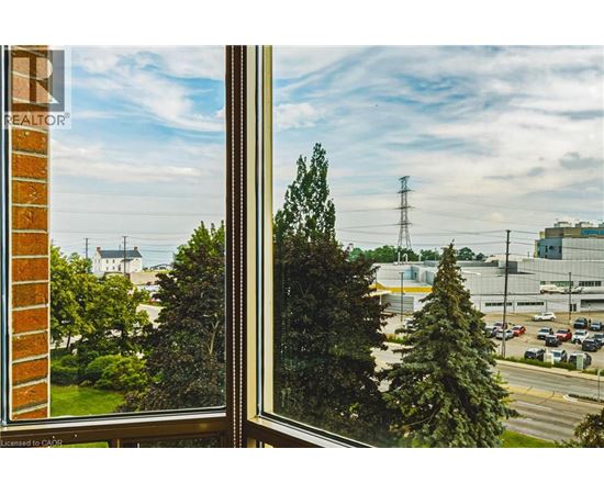 A view from a window looking out at a parking lot and a large building.