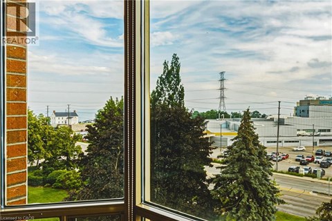 A view from a window looking out at a parking lot and a large building.