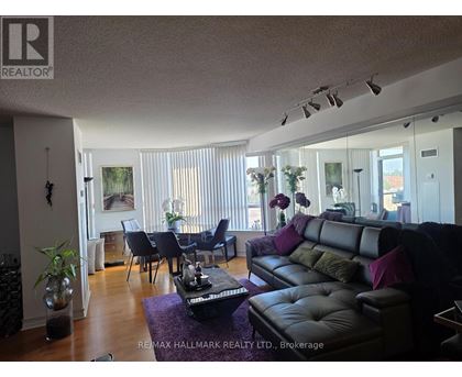 A living room with a black leather couch and a dining table with chairs.