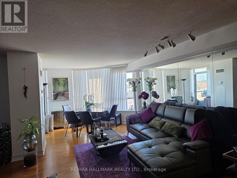 A living room with a black leather couch and a dining table with chairs.