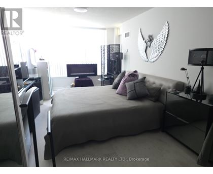 A bedroom with a large bed and a wall hanging of a bird.