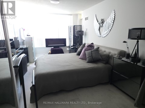 A bedroom with a large bed and a wall hanging of a bird.