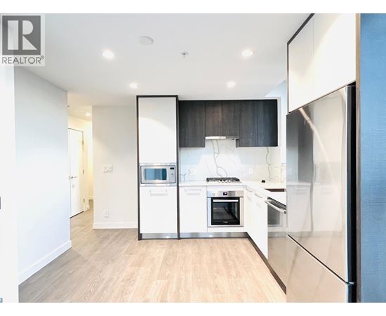 A modern kitchen with white appliances and wooden floors.