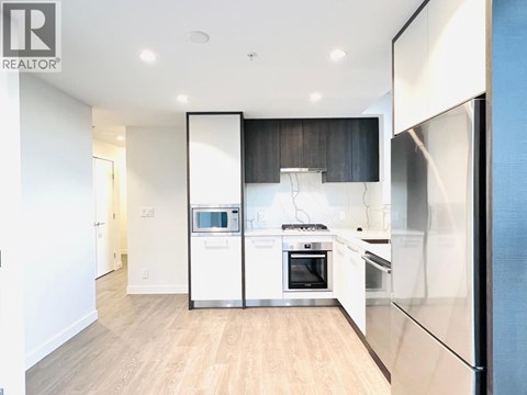 A modern kitchen with white appliances and wooden floors.