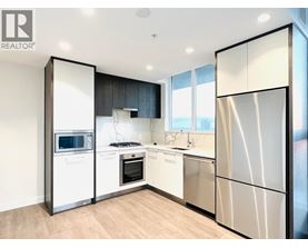 A modern kitchen with a refrigerator, microwave, oven, and sink.