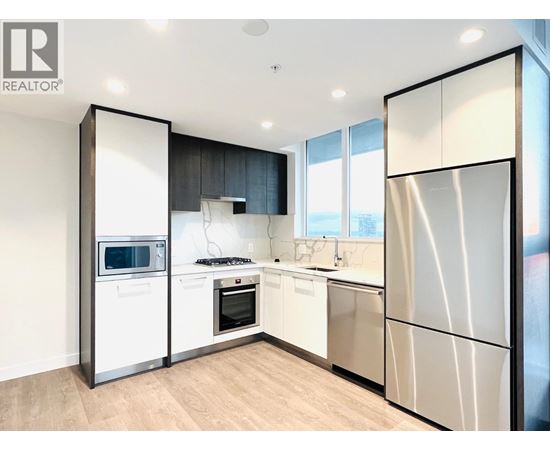 A modern kitchen with a refrigerator, microwave, oven, and sink.