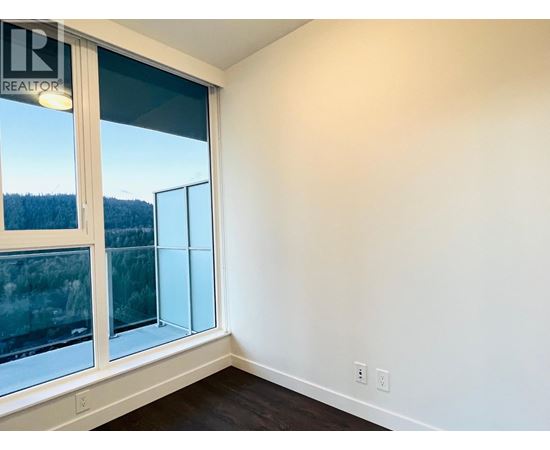 A room with a large window and a view of trees outside.