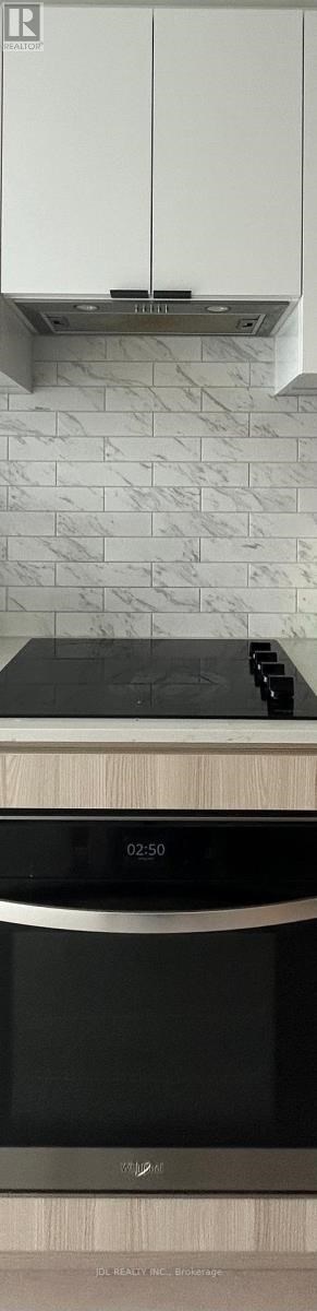 A modern kitchen with a black oven and white cabinets.