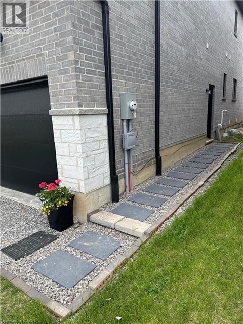 A grey brick building with a black door and a grey stone walkway.