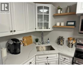 A kitchen with white cabinets and a marble countertop.
