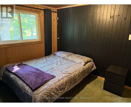 A bedroom with a bed, a window, and a wooden headboard.