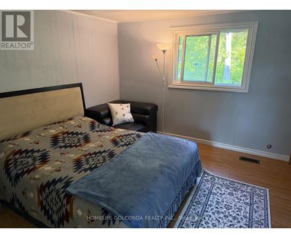 A bedroom with a bed, a chair, and a window.