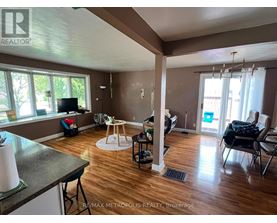 A living room with a television, a dining table, and chairs.