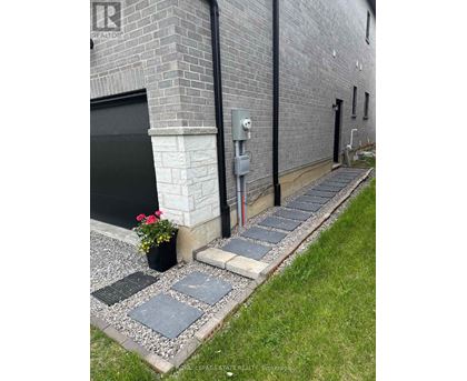 A brick building with a black door and a grey stone walkway.
