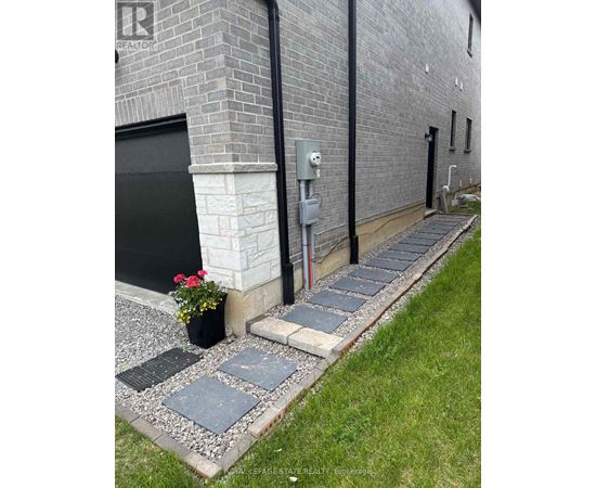 A brick building with a black door and a grey stone walkway.