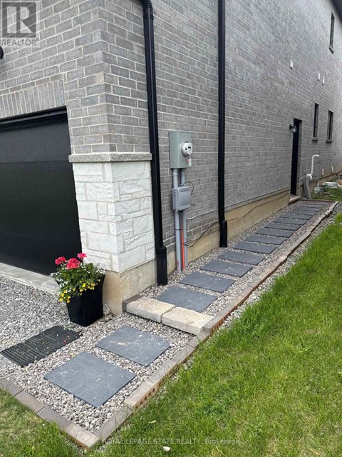 A brick building with a black door and a grey stone walkway.