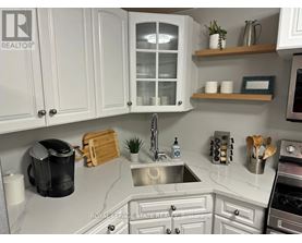 A kitchen with white cabinets and a marble countertop.