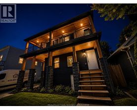 A house with a dark front door and a lit up porch.