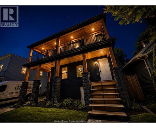 A house with a dark front door and a lit up porch.