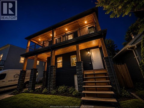 A house with a dark front door and a lit up porch.